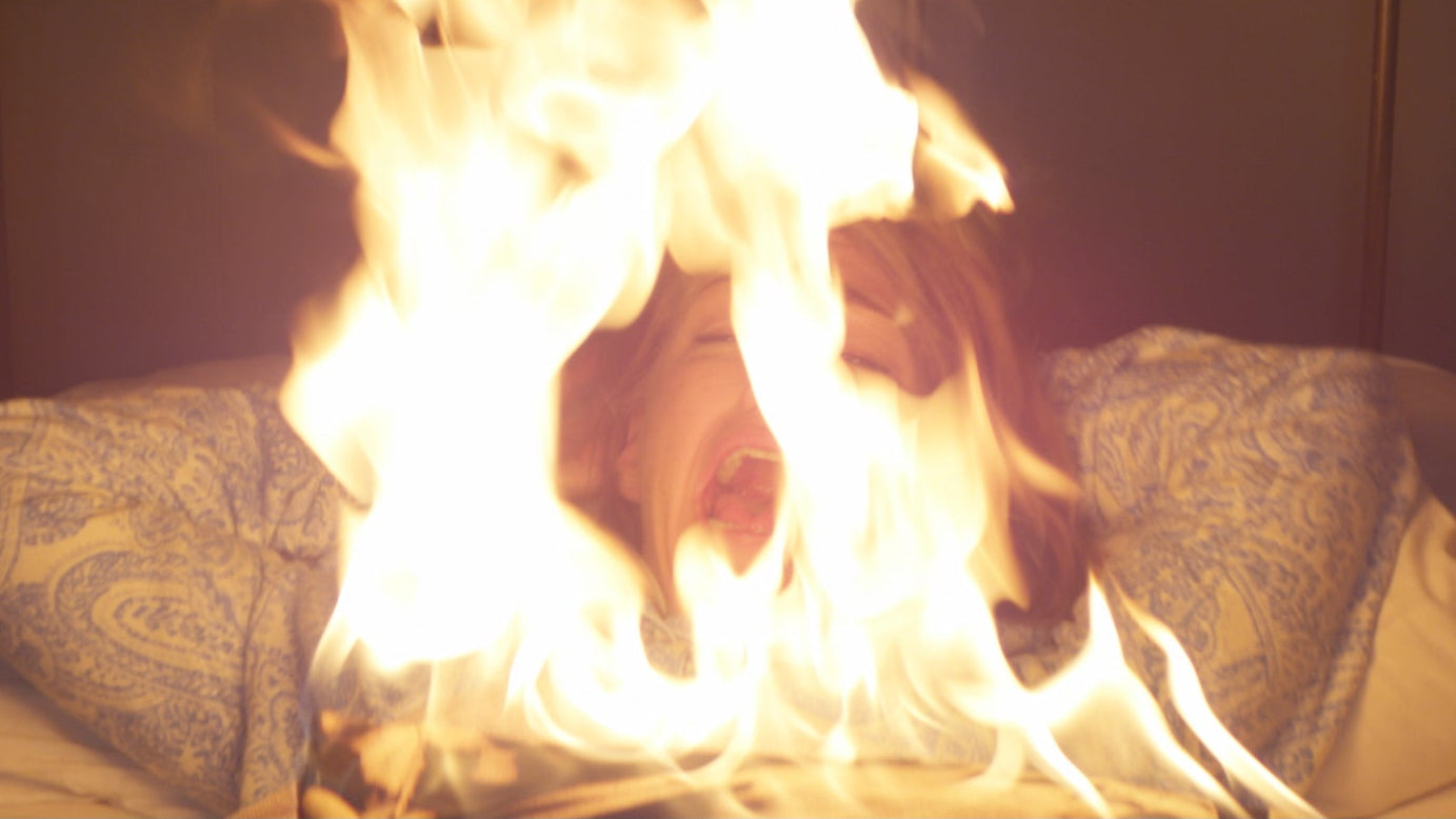 Flames burning on a bed with patterned pillows