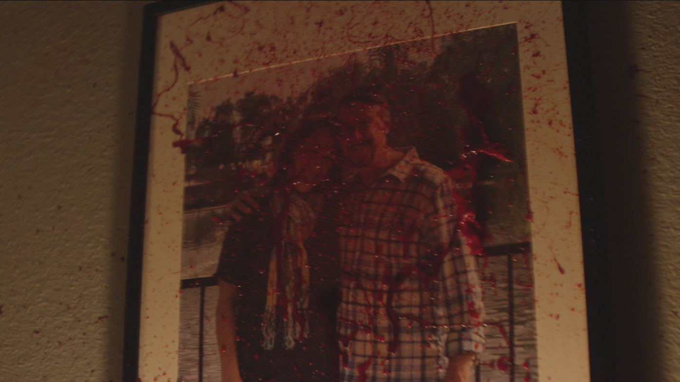 Vintage photo of a person with a plaid shirt and wreath, bloodstains on the edges.