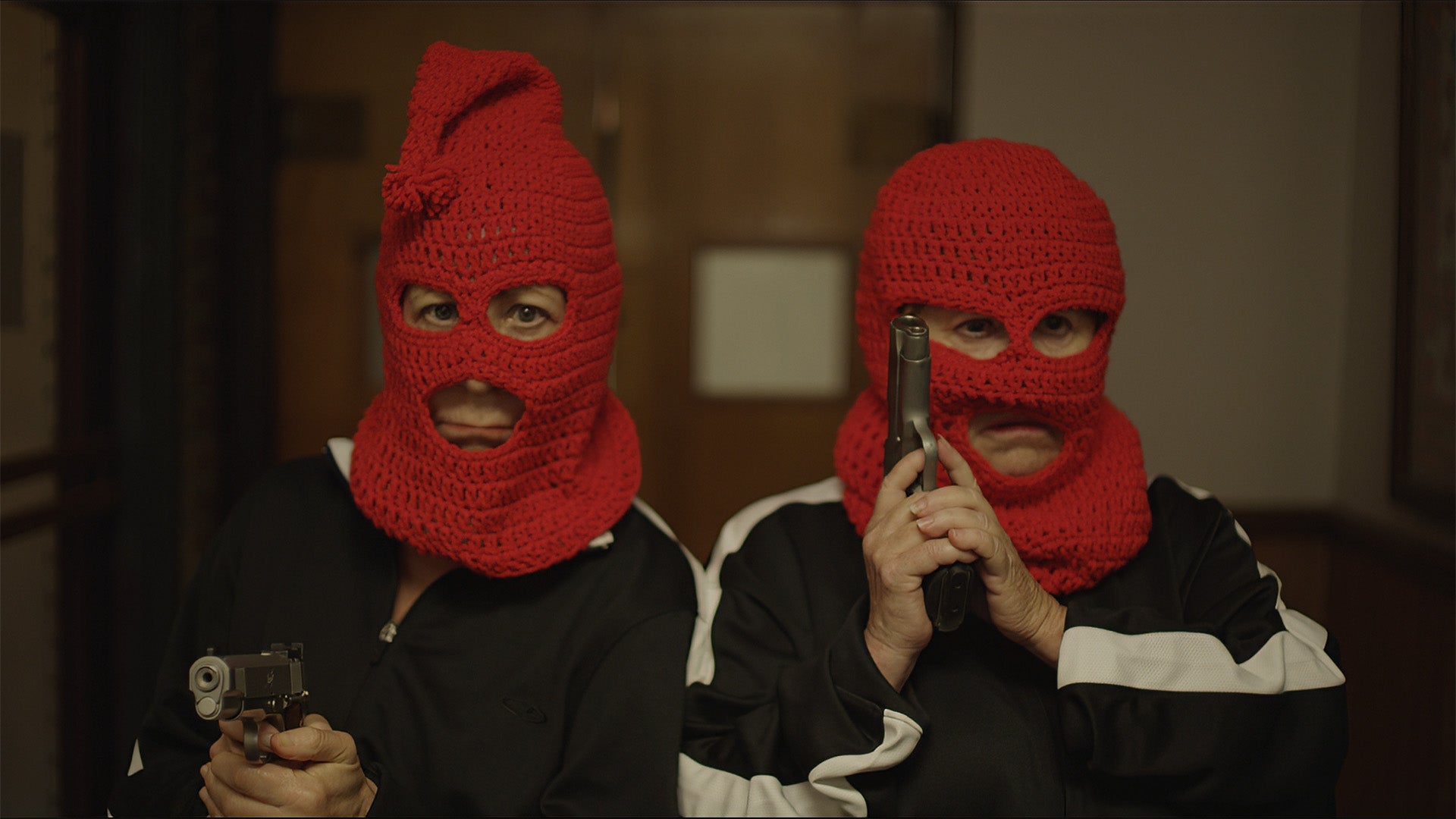 Two individuals wearing red balaclavas holding guns indoors.