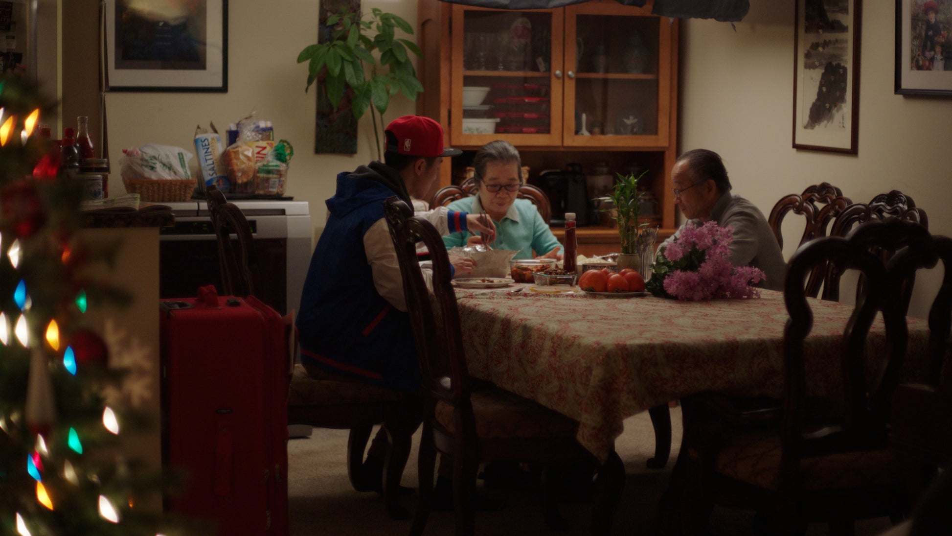Family gathered around a dining table in a home setting with Christmas decorations.