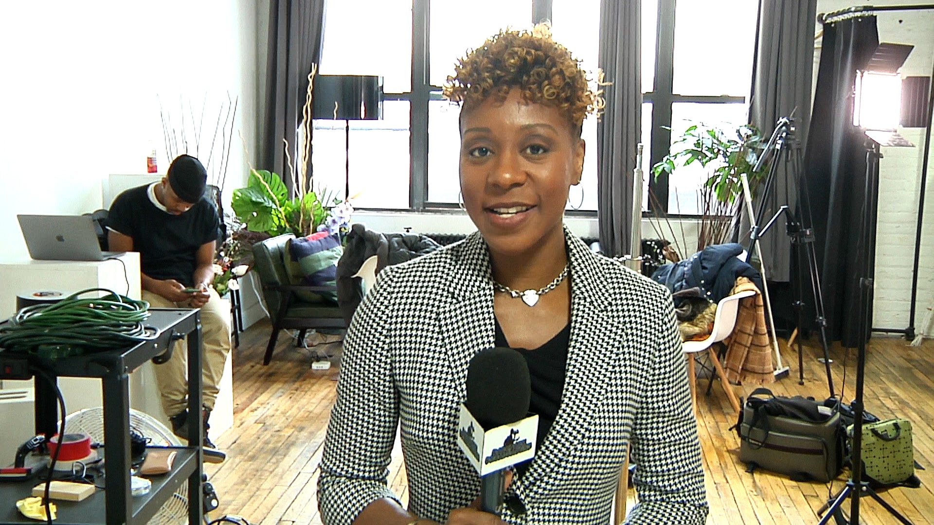 Woman holding a microphone in a room with filming equipment