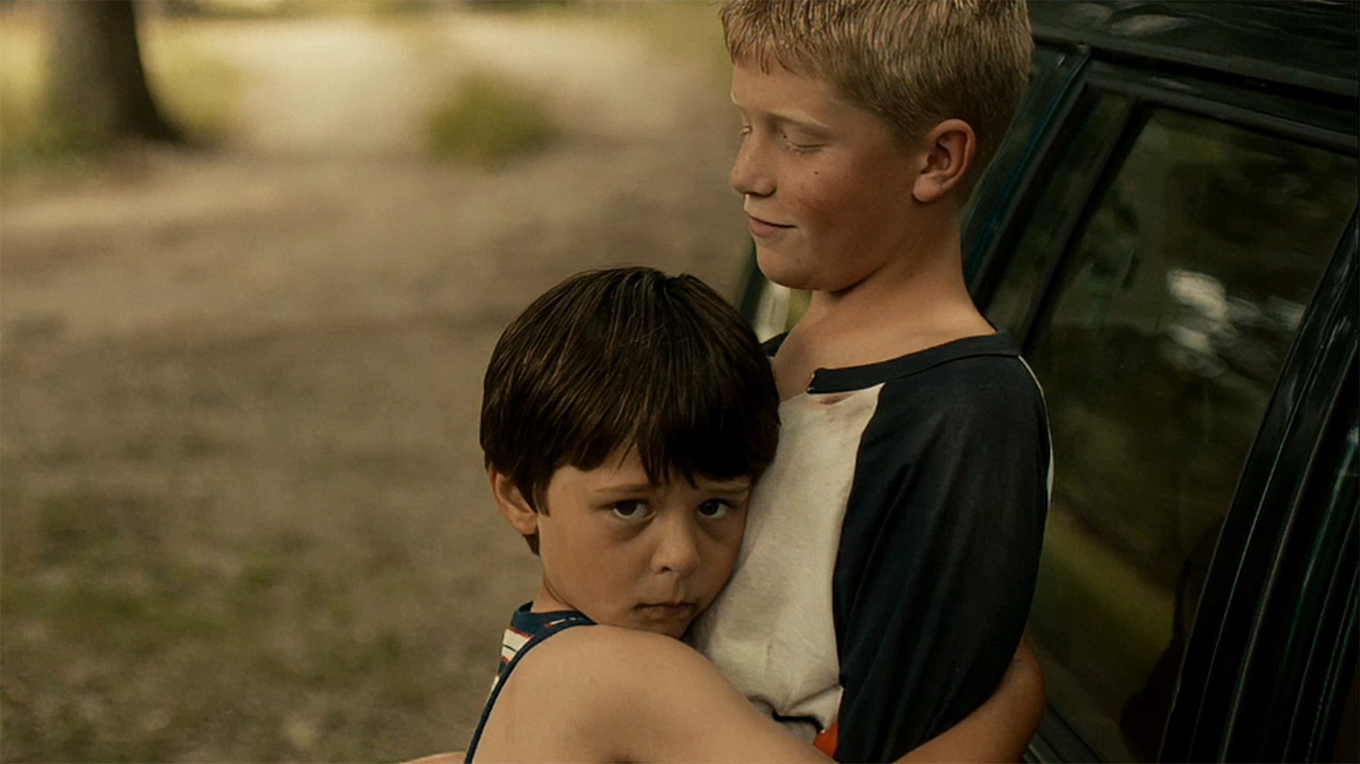 Two young boys standing outdoors with a blurred background