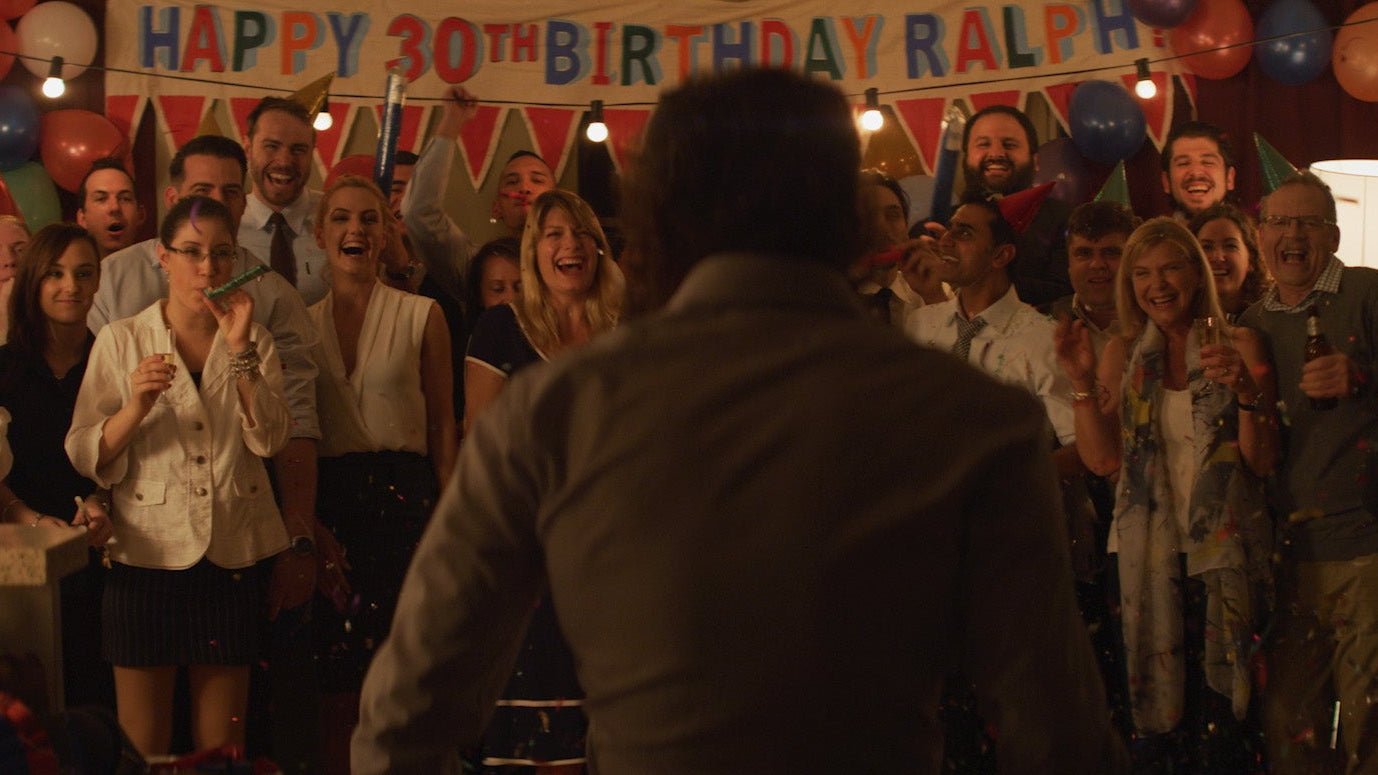 Group of people celebrating a 30th birthday party with balloons and decorations.