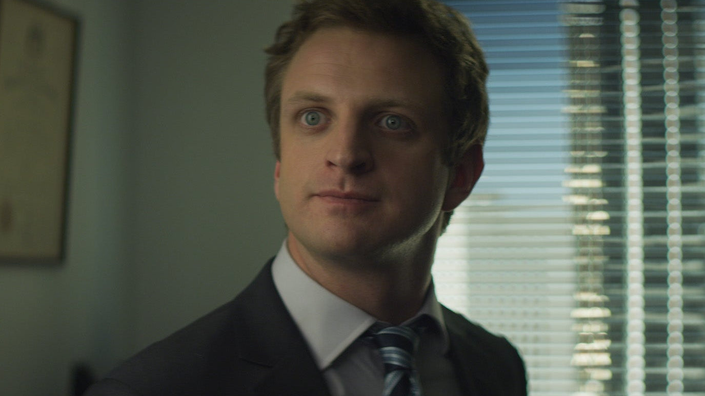 Man in a suit standing in an office with a window in the background