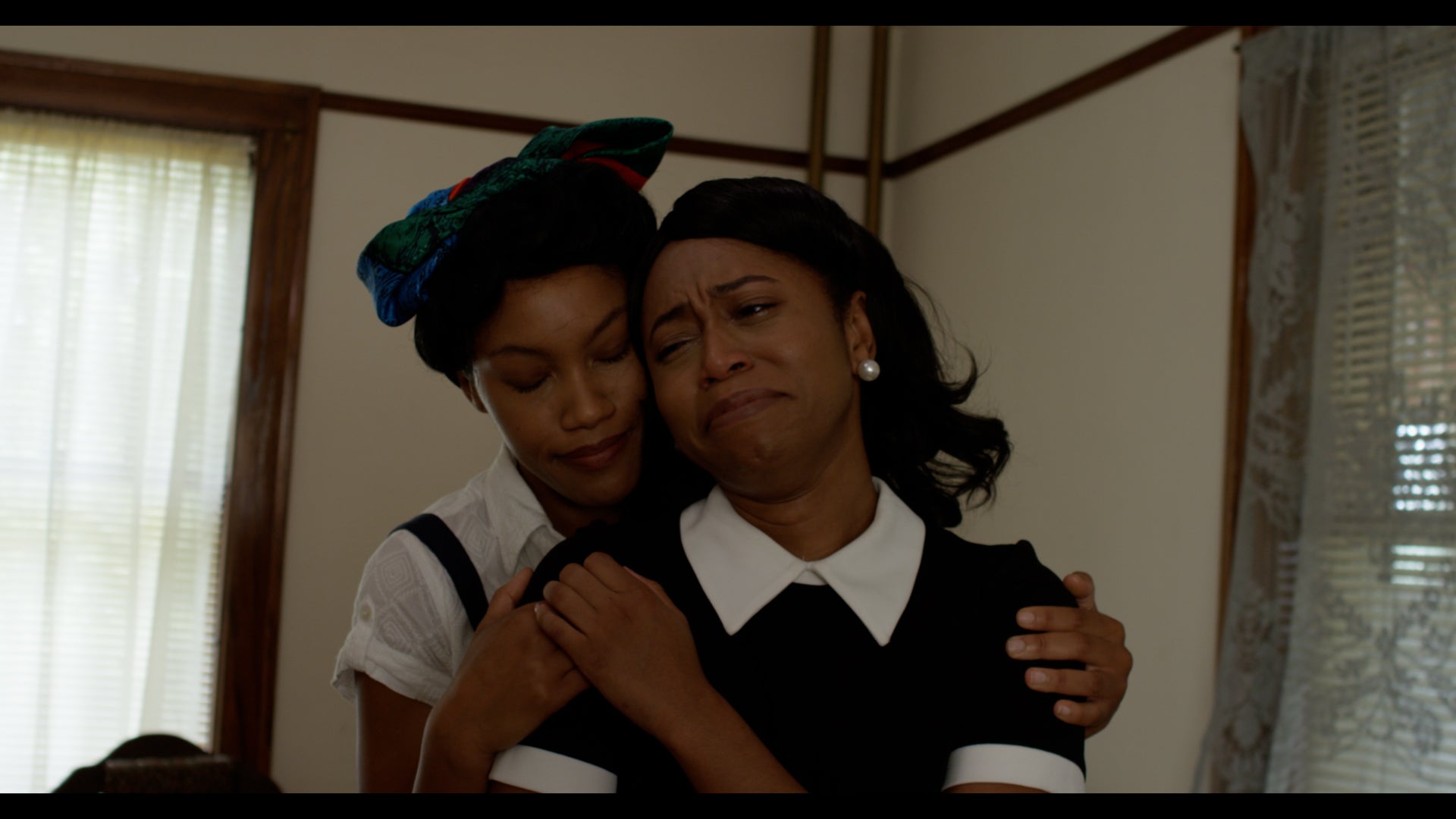 Two women embracing each other indoors with a neutral background