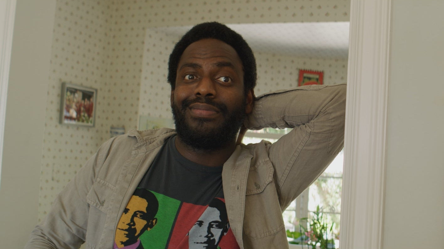 Man in a room with a mirror and framed picture on the wall
