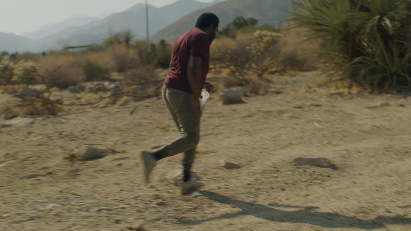 Person running on a dirt path in a desert landscape with mountains in the background