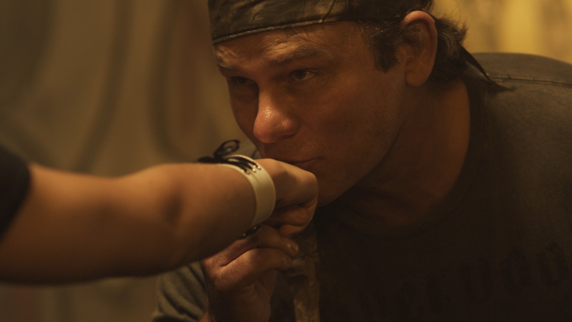 Person with a bandage on their hand approaching another person in a close-up shot.