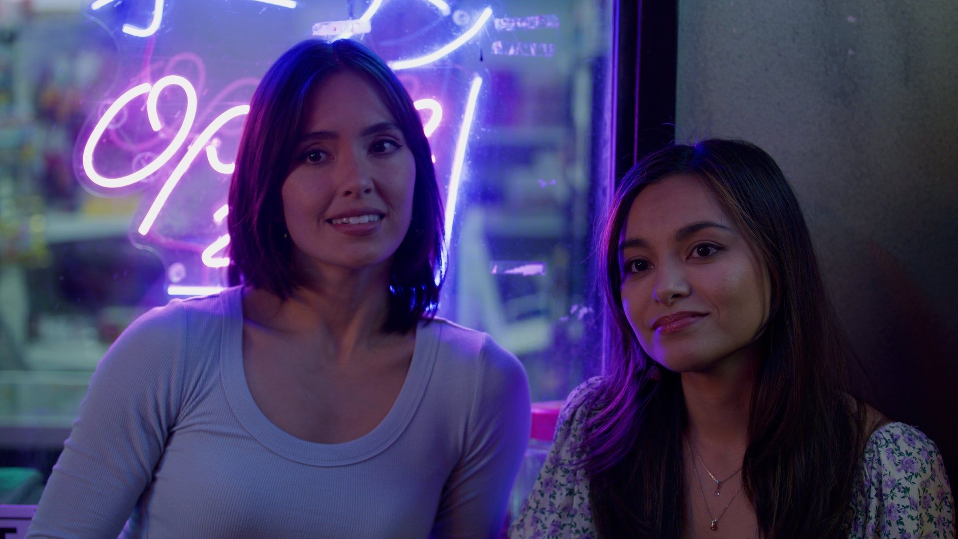 Two men in a room with a brick wall and multiple televisions displaying different images.
