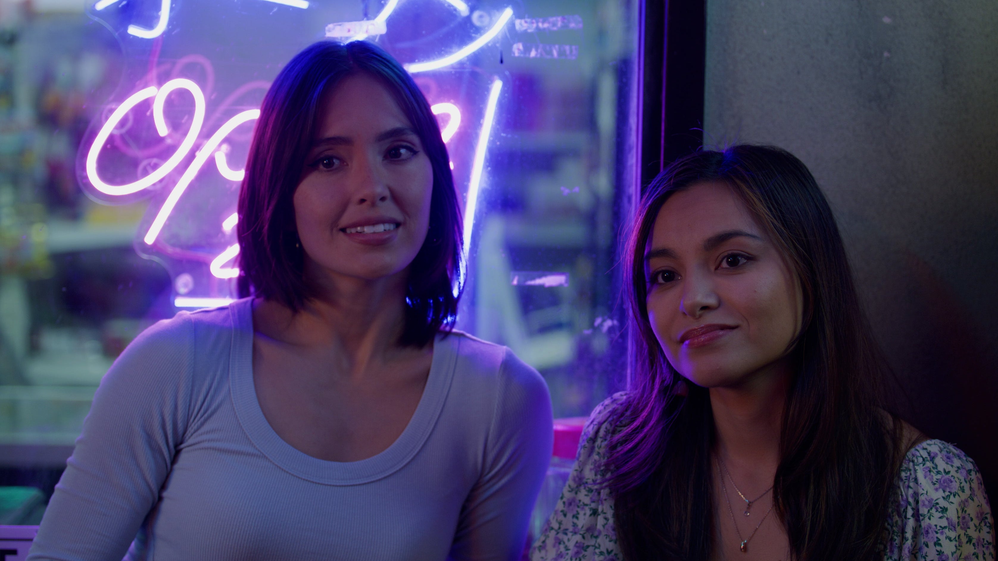 Two men in a room with a brick wall and multiple televisions displaying different images.