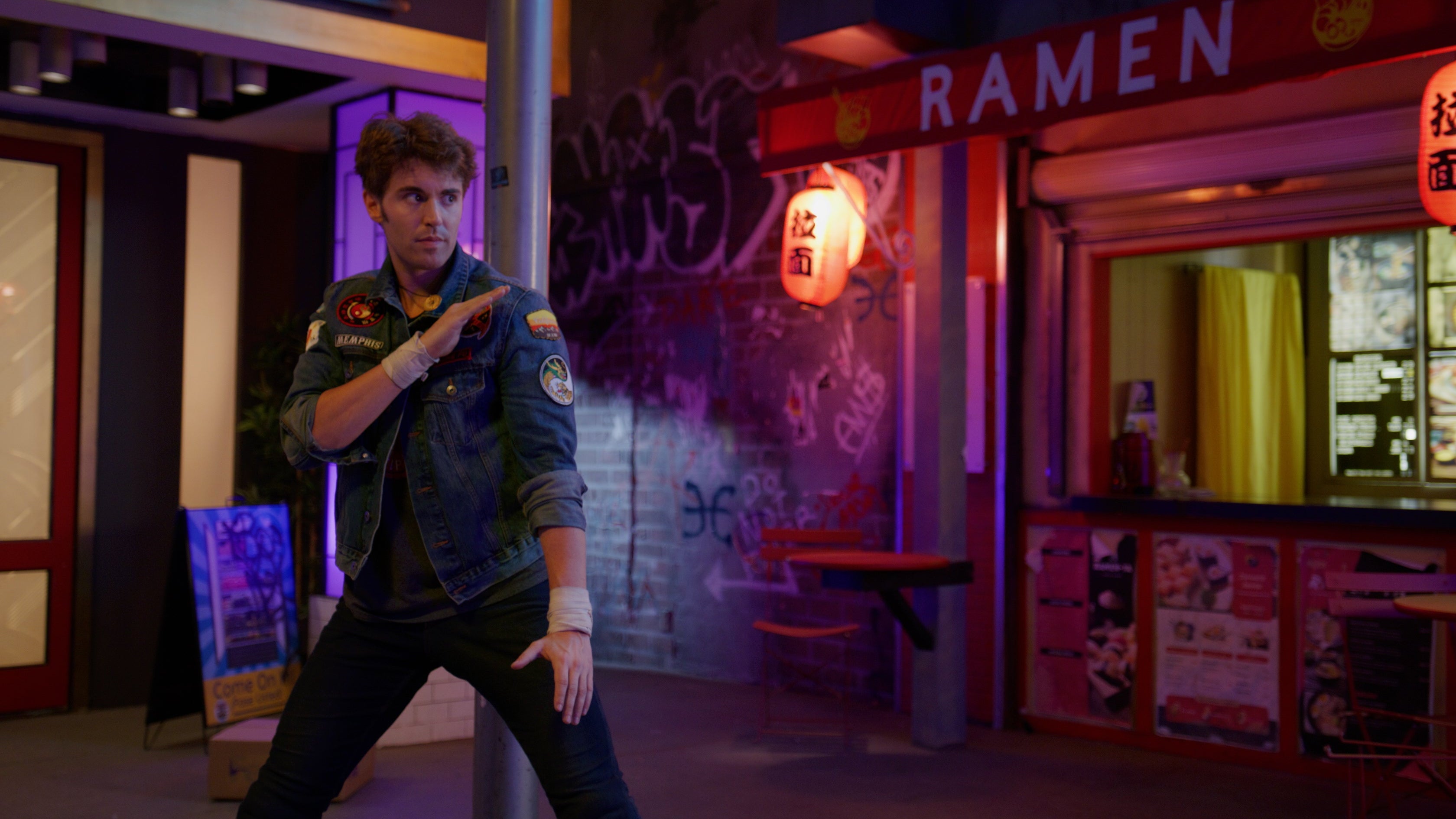 Person in a colorful room with 'Ramen' sign and neon lights