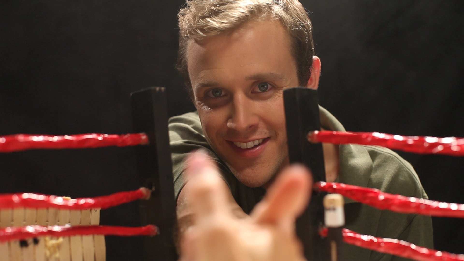 Person holding a smartphone with a boxing ring background