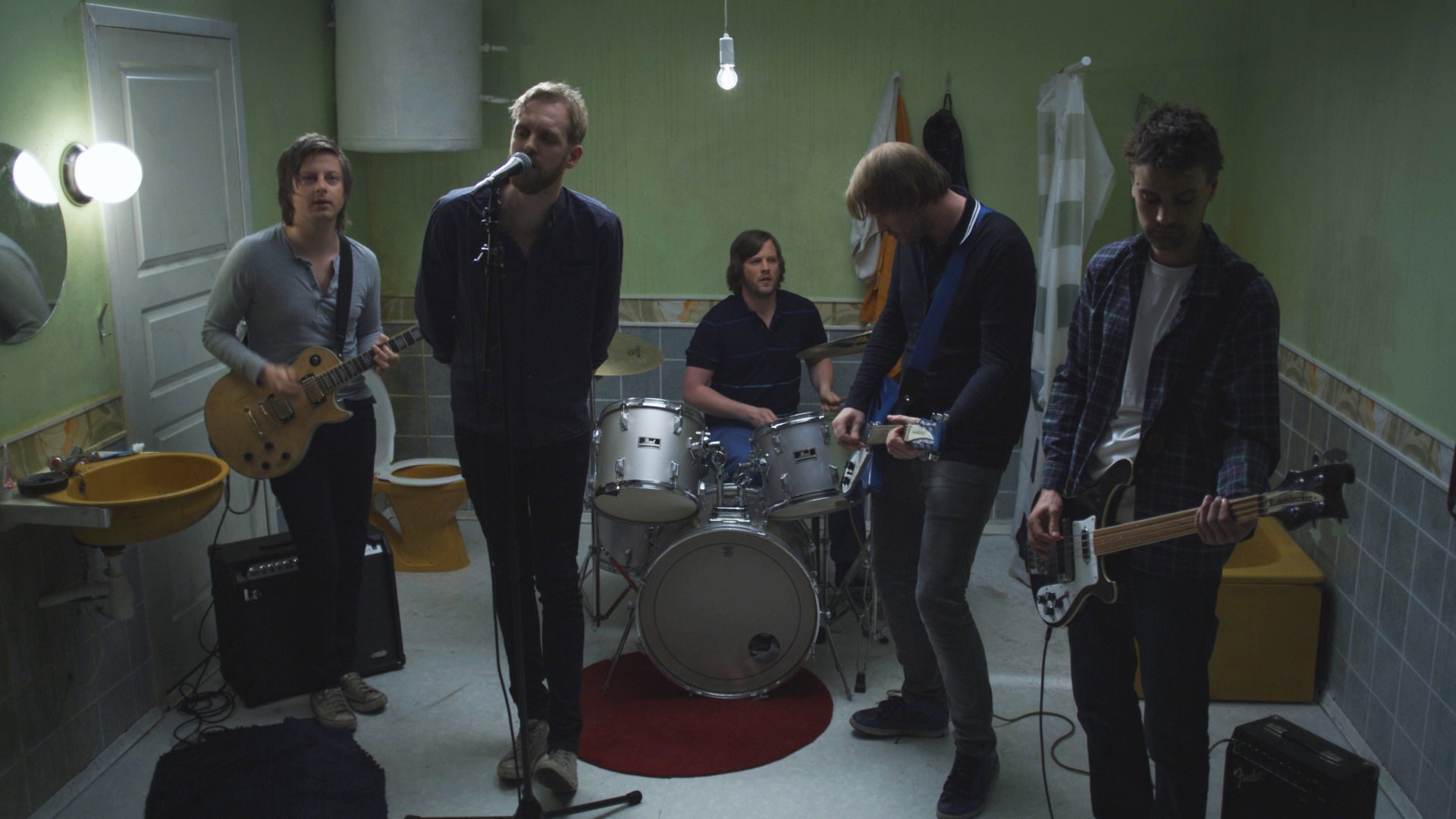 Band playing in a room with green walls and tiled floor