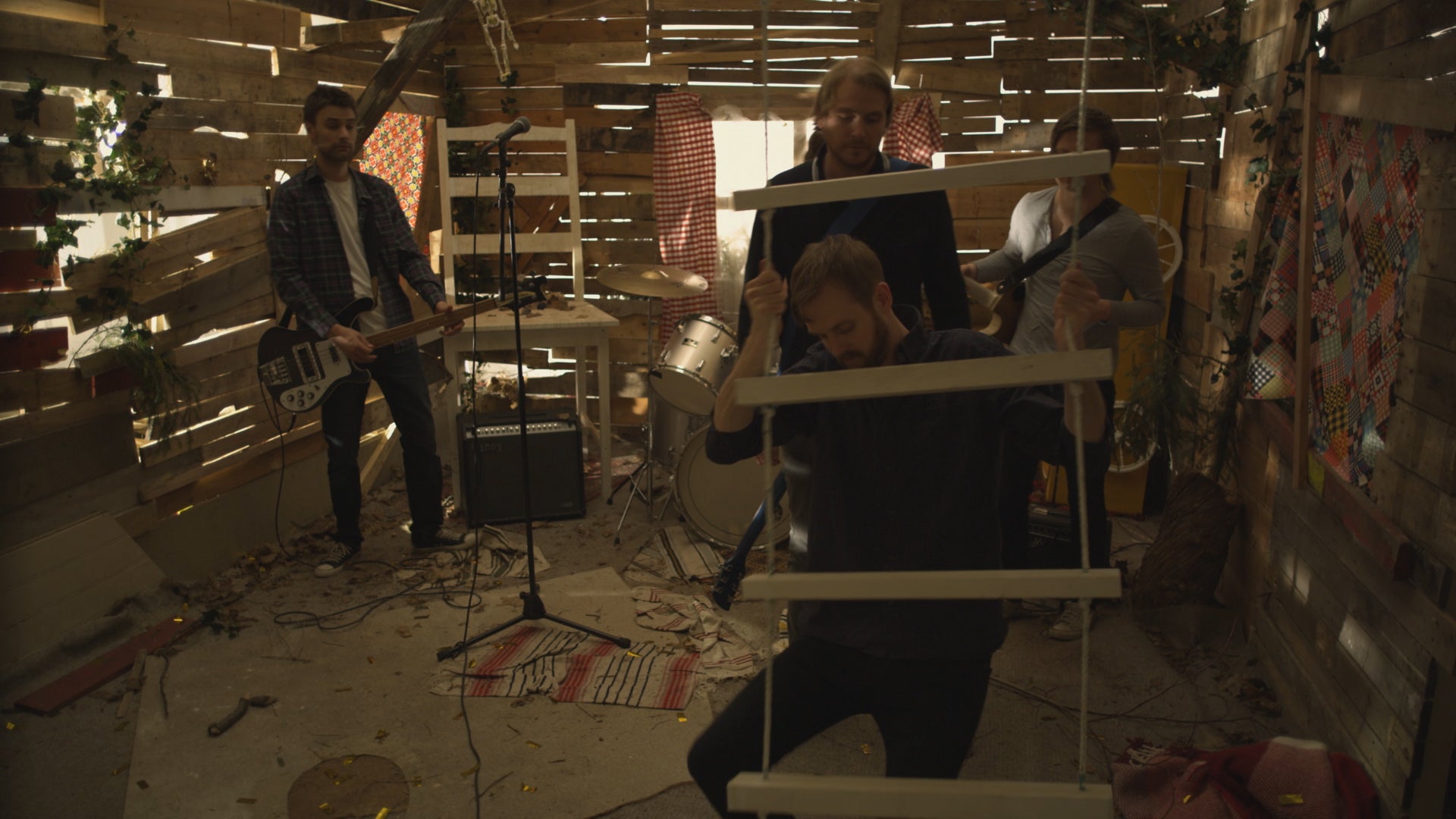 Group of people in a chaotic room with debris and a person holding a ladder.