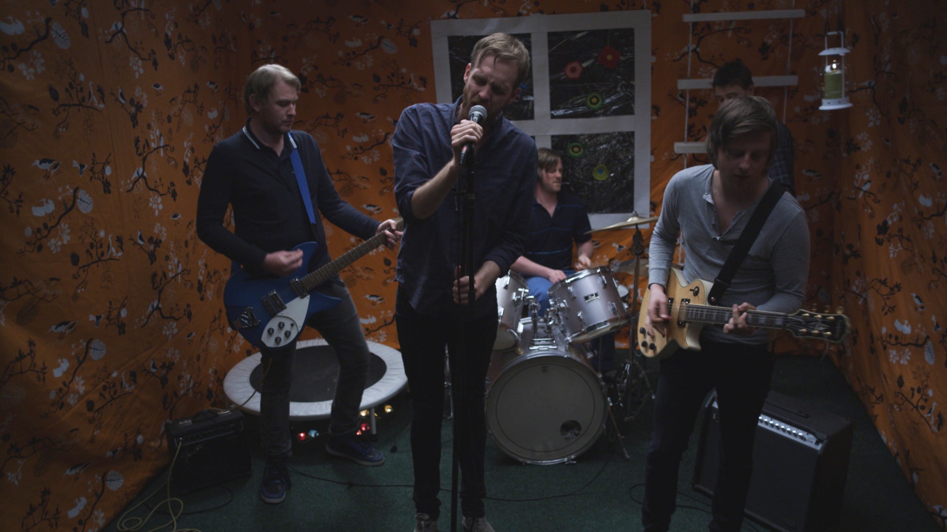 Band performing on stage with instruments and a microphone.