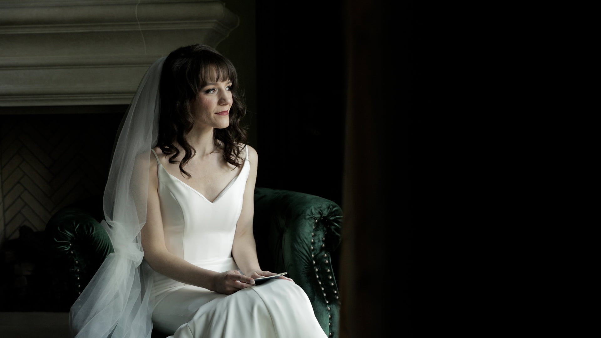 Woman in a white wedding dress sitting on a green couch.